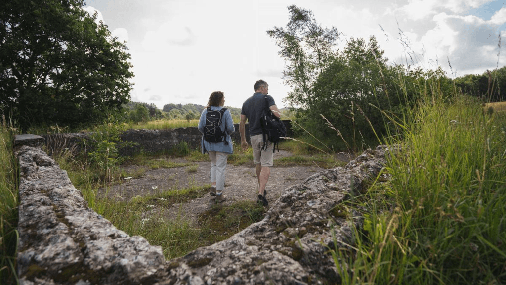 A couple walks among the ruins of the old bathing facility at the source of the Gudenå River